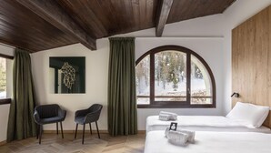 A room with two beds, a wooden ceiling, a large arched window with a snowy view, and a geometric wall art piece. - B&B Hotel Passo Tre Croci Cortina (Cortina d'Ampezzo)