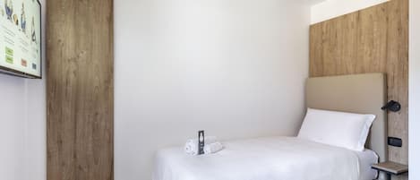 Une chambre d’hôtel avec un lit, un mur décoratif en bois, une petite table de chevet et un téléviseur fixé au mur.