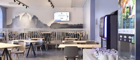 A modern restaurant with a digital menu display, seating area, and a wall mural.