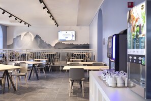 A modern restaurant with a digital menu display, seating area, and a wall mural. - B&B Hotel Passo Tre Croci Cortina (Cortina d'Ampezzo)
