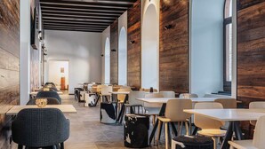 A modern restaurant interior with wooden walls, multiple tables and chairs, and a long counter.