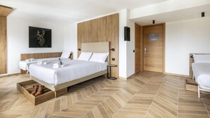 A modern hotel room with a large bed, a wooden headboard, a wooden floor, and a wall-mounted artwork. - B&B Hotel Passo Tre Croci Cortina (Cortina d'Ampezzo)