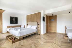 Una habitación de hotel moderna con una cama grande, un cabecero de madera, suelo de madera y una obra de arte colgada en la pared.