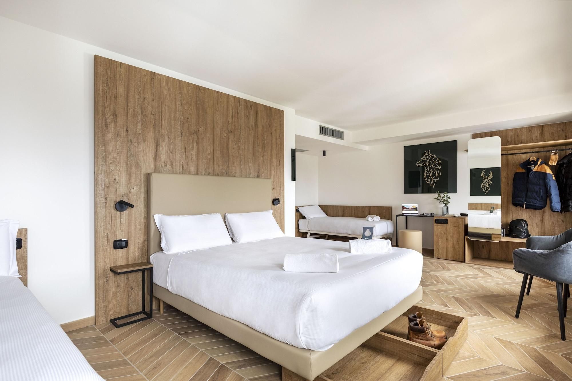 Ein modernes Hotelzimmer mit einem großen Bett, einem Schreibtisch, einem Sessel und einem Kleiderschrank.