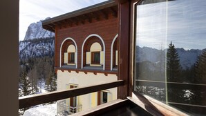 A wooden building with arched windows and a balcony, overlooking a snowy mountain landscape.