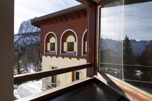 A wooden building with arched windows and a balcony, overlooking a snowy mountain landscape. - B&B Hotel Passo Tre Croci Cortina (Cortina d'Ampezzo)