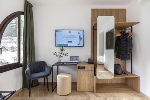 A modern hotel room with a desk, chair, laptop, and a TV displaying a welcome message. - B&B Hotel Passo Tre Croci Cortina (Cortina d'Ampezzo)