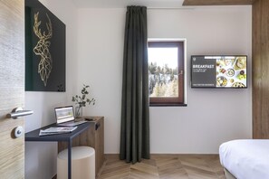 A modern room with a desk, laptop, and a window with curtains.