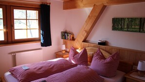 A bedroom with a bed, checkered bedding, a nightstand, a lamp, a bookshelf, and a painting. - Apartment 'Feldberg' with Shared Garden, Balcony and Wi-Fi (Hinterzarten)