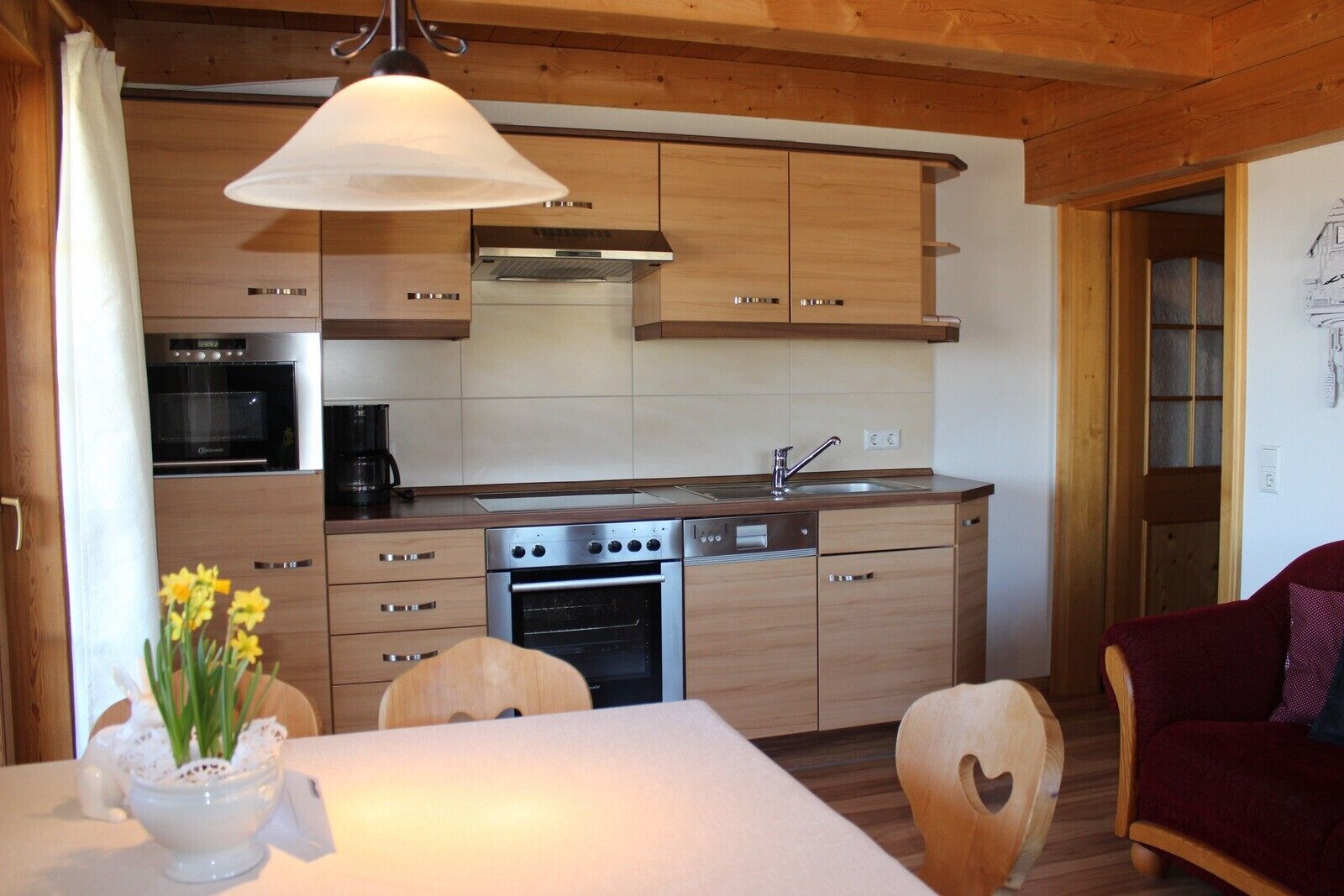 Eine kleine Küche mit Holzausstattung, Backofen, Geschirrspüler und Kaffeemaschine.