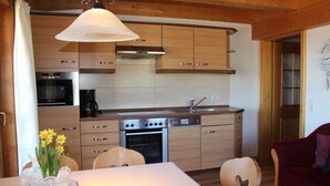 Una cocina compacta con gabinetes de madera, horno empotrado, lavavajillas y cafetera.