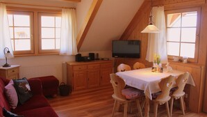 Una habitación acogedora con una mesa de comedor, sillas, un televisor y un sofá rojo.