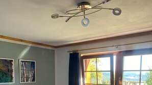 Een slaapkamer met een bed, een raam met gordijnen, een plafondventilator en een radiator.