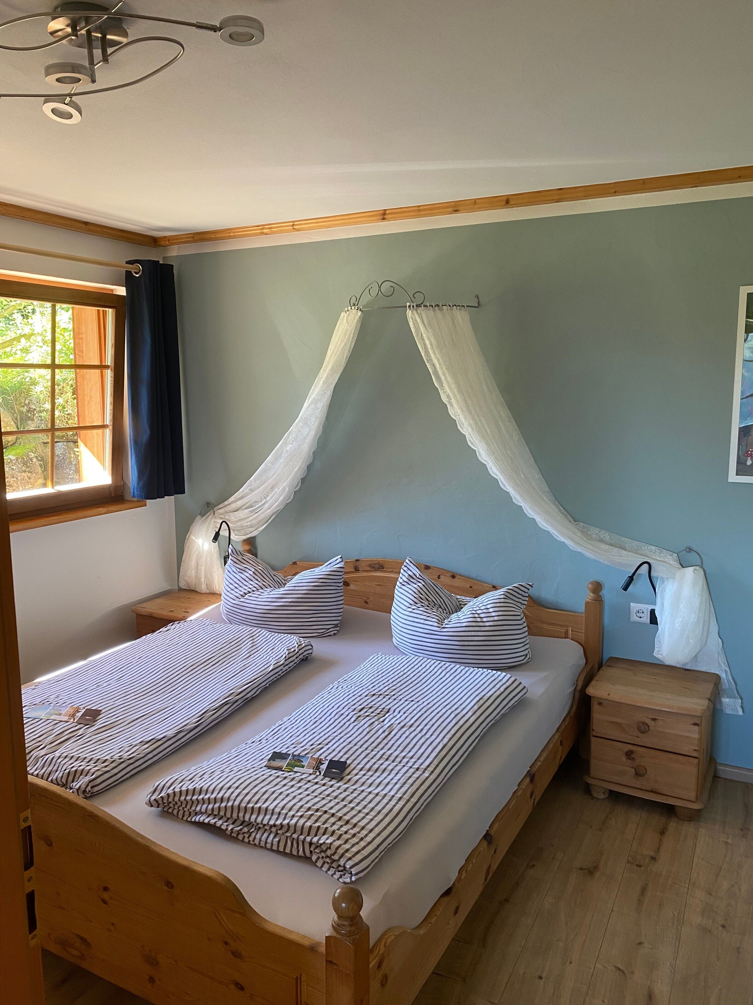 A bed with a canopy, striped bedding, a bedside table, and a nightstand.