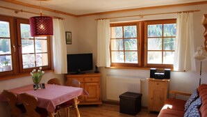 Een gezellige kamer met een eettafel, stoelen, een bank, een televisie en een radiator.