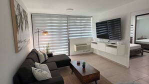 Una sala de estar moderna con un sofá, una mesa de centro, un televisor y un comedor.