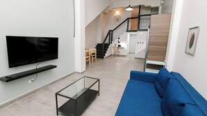 Una sala de estar moderna con un televisor de pantalla plana, un sofá azul y una mesa de centro de vidrio.