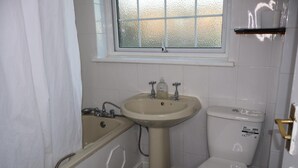 Un baño con bañera, lavamanos e inodoro.