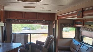 Un intérieur de camping-car compact comprenant un coin cuisine, un espace salon et une fenêtre donnant sur l’extérieur.