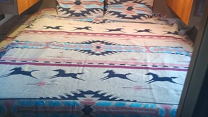 Un lit avec une couvre-lit à motifs et deux oreillers, une tête de lit en bois et une petite table de chevet.