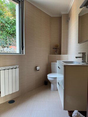 Ein modernes Badezimmer mit Toilette, Waschbecken und Fenster.