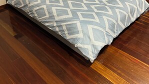 A bed with a geometric patterned bedspread, a dark headboard, and a blue towel. - Charming 3-bedroom cottage with AC in Torbanlea (Torbanlea)