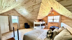 Un dormitorio acogedor en el ático con una cama litera, un escritorio y una silla.