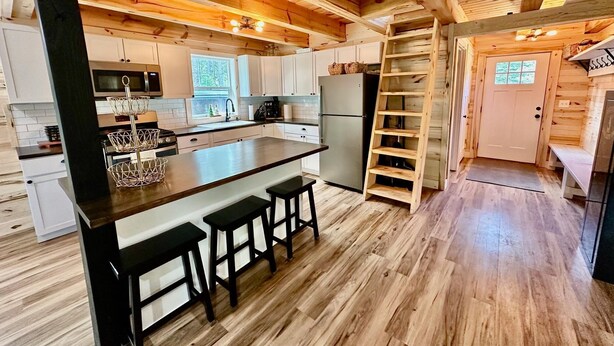 Una cocina de estilo cabaña de madera con una isla central, armarios empotrados y una estantería tipo escalera.