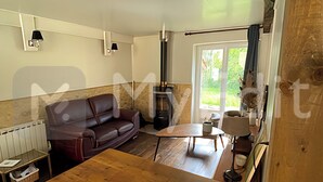 A cozy living room with a wooden table, a leather sofa, and a fireplace. - EDEN gîte for 2 people with terrace and swimming pool in the heart of the Périgord Noir region (Doissat)