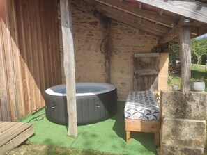 A hot tub, a wooden bench, and a stone wall in a rustic outdoor setting. - EDEN gîte for 2 people with terrace and swimming pool in the heart of the Périgord Noir region (Doissat)