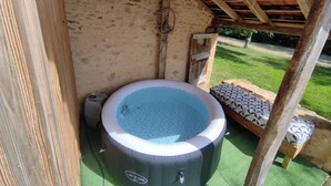 A hot tub under a wooden pergola with a stone wall backdrop. - EDEN gîte for 2 people with terrace and swimming pool in the heart of the Périgord Noir region (Doissat)