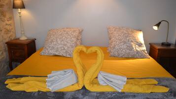 A bed with a heart-shaped towel arrangement, patterned pillows, and bedside lamps.
