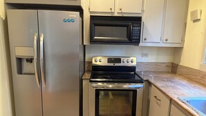 Una cocina con un refrigerador de acero inoxidable, un microondas y un horno.