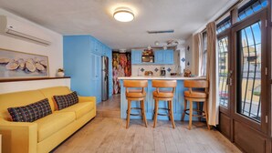 A kitchen with blue cabinets, a yellow sofa, and a bar area. - Medano Beach, Marina, Downtown, Walkable, Cozy (Cabo San Lucas)