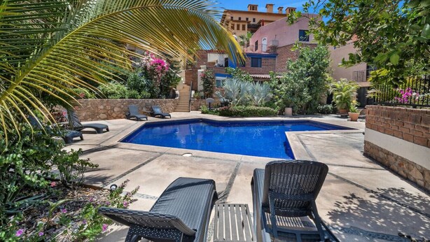 A swimming pool with lounge chairs and a stone wall. - Medano Beach, Marina, Downtown, Walkable, Cozy (Cabo San Lucas)