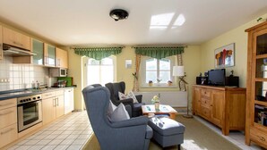 A compact living space with a kitchenette, a sofa, a television, and a dining area.