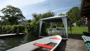 A boat docked at a pier with a covered seating area and a view of a residential area.