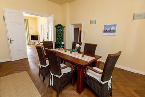 Un comedor con mesa de madera, sillas de mimbre y un armario verde.