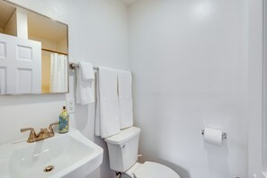 Une salle de bain avec un lavabo blanc, des toilettes et un rideau de douche.