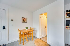 A dining area with a wooden table and chairs, a small potted plant, and a framed picture on the wall. - Waterbury Studio 12 Mi to Bolton Valley Ski Resort (Waterbury)