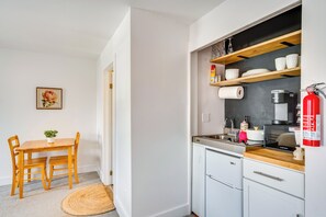 Une cuisine de taille réduite, dotée de meubles en bois, d’une machine à café et d’un extincteur.