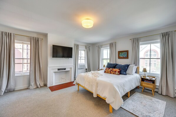 A bedroom with a bed, bedside table, lamp, and a flat-screen TV mounted on the wall. - Waterbury Studio 12 Mi to Bolton Valley Ski Resort (Waterbury)