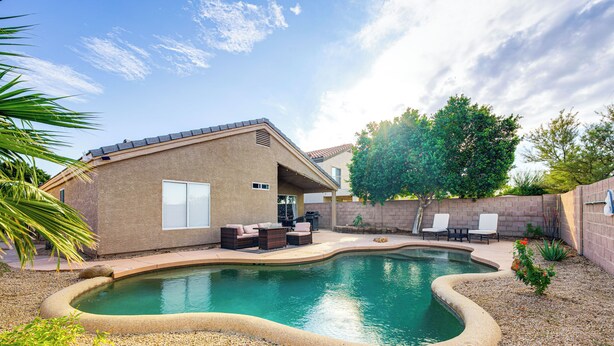A backyard with a swimming pool, patio furniture, and a brick house. - Swim & Unwind: 'Wildrose Retreat' in Mesa! (Mesa)