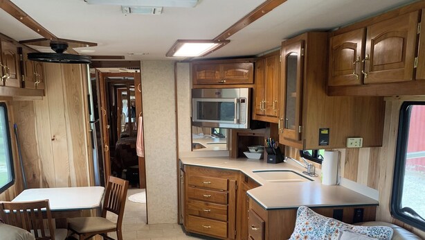 Un intérieur de camping-car compact comprenant un coin cuisine, un espace repas et un coin salon.