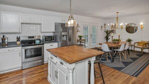 Een moderne keuken met witte kasten, roestvrijstalen apparatuur en een houten keukeneiland.