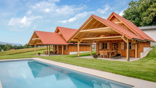 Eine Holzhütte mit Schwimmbad, Sitzgelegenheit im Freien und Blick auf die Landschaft.