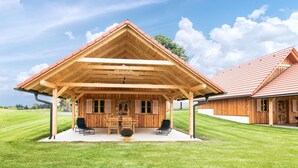 Eine Holzhütte mit überdachter Terrasse, Essbereich und großem Rasen.