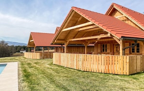 A row of wooden cabins with red roofs, a wooden deck, and a swimming pool. - Lovely home in Stainz with heated swimming pool (Stainz)