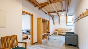 A cozy room with a wooden bench, a wooden wardrobe, a bench with a cushion, and a small table.
