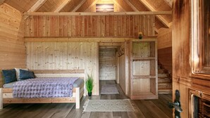 Ein Holzblockhaus mit Bett, Treppe und einer kleinen Pflanze.